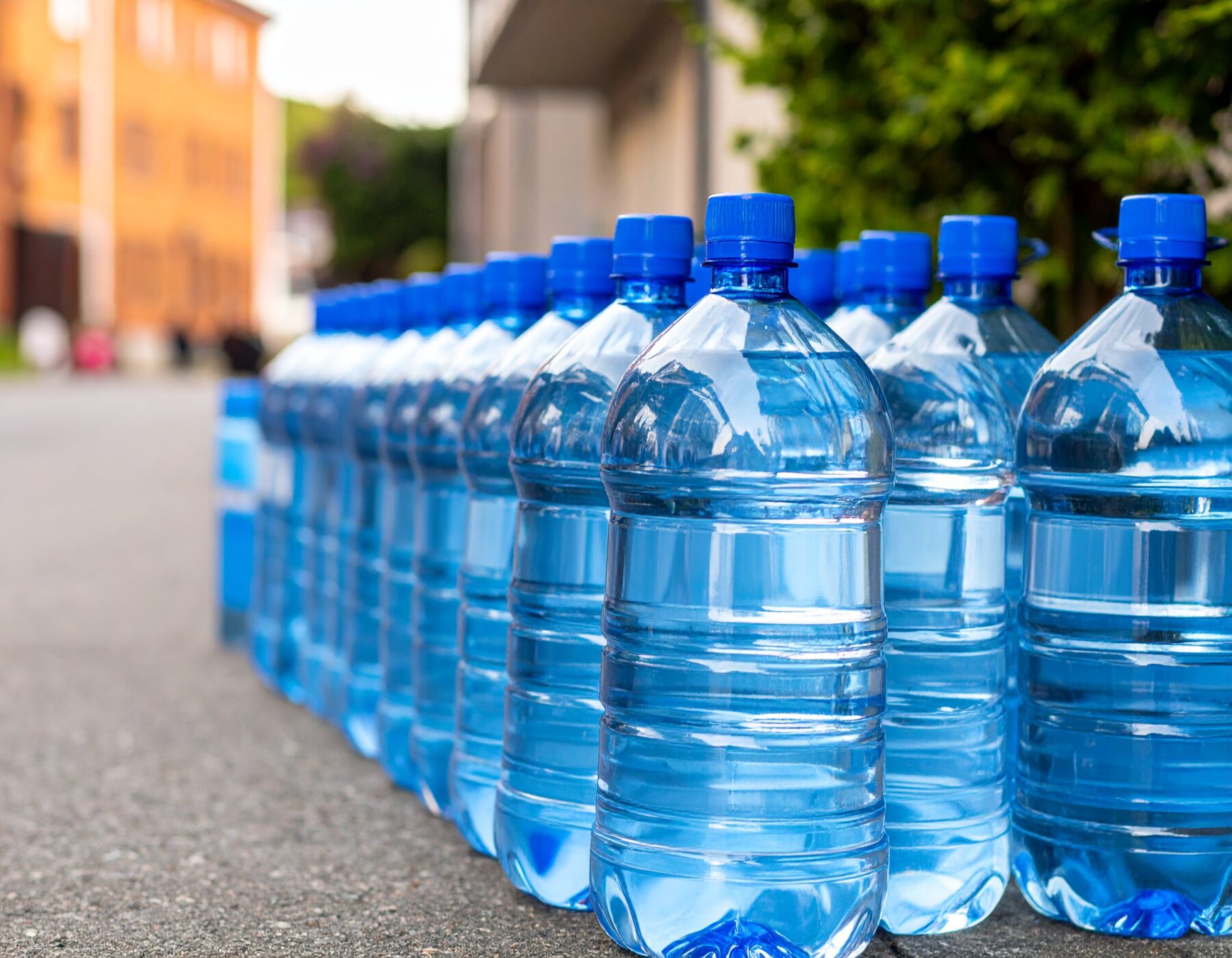 A row of bottles of drinking water waiting on a Scandinavian looking street (Photo AI generated with Adobe Firefly)